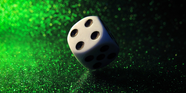 Dice showing 4 on a green flitter background