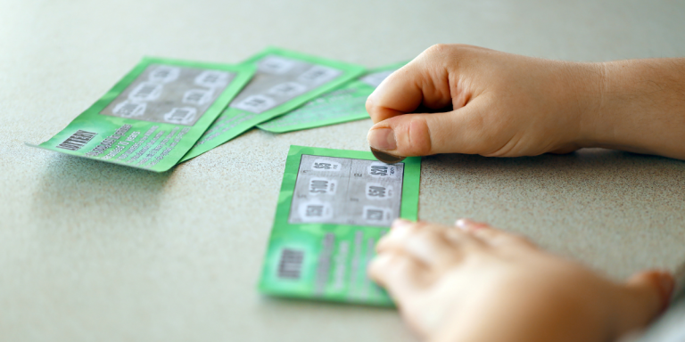 Hands scratching off a scratch card with a penny