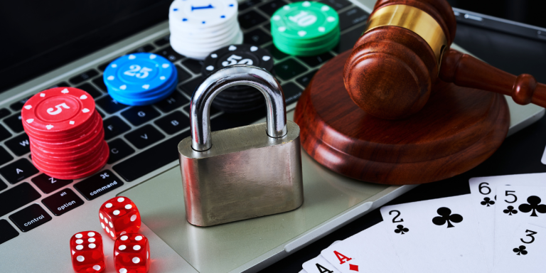 Laptop underneath gambling chips, dice, a padlock and a barrister's gavel